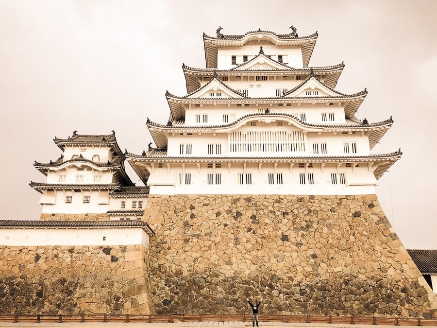 Un pequeño viajero posando con el enorme castillo de Himeji en Japón