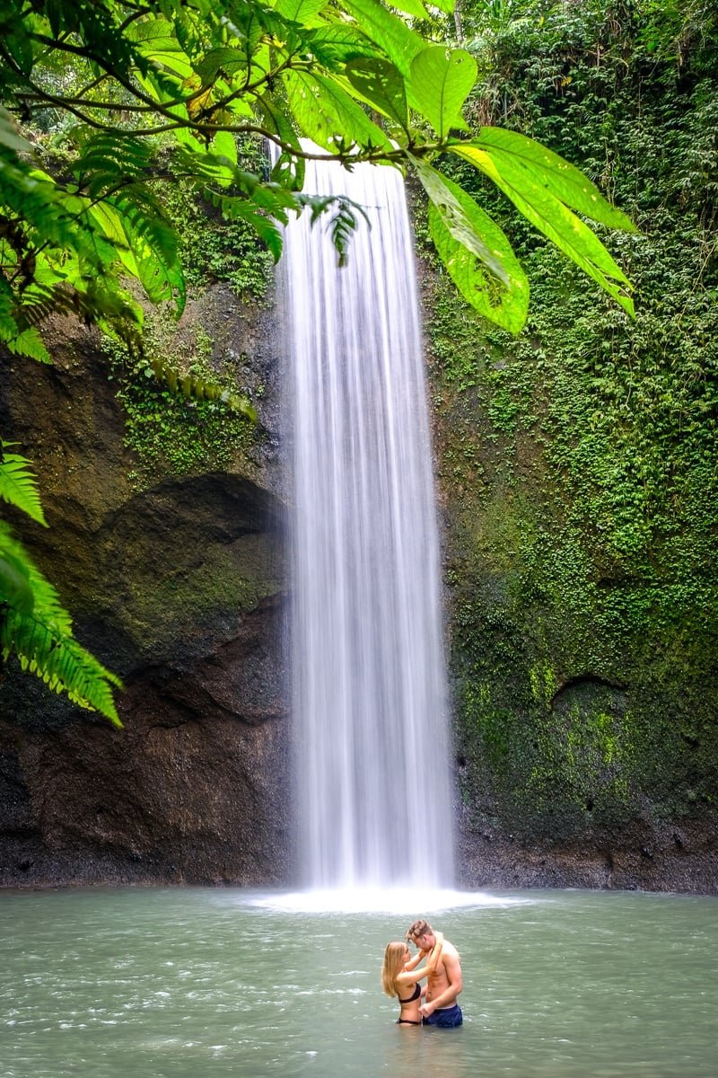 Pareja de turistas posando en la cascada Tibumana en Bali