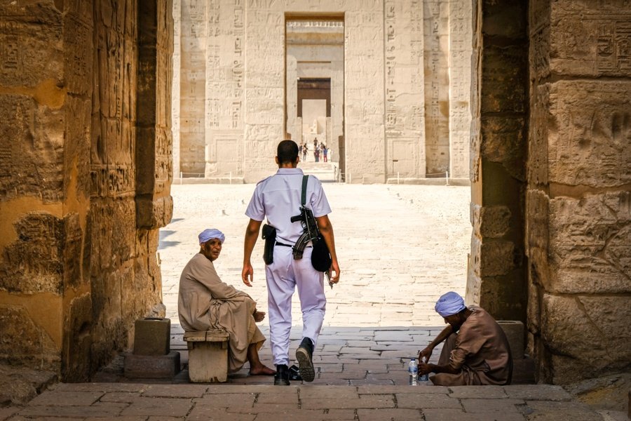 Policía guardia de seguridad y mendigos en el templo de Medinet Habu en Egipto