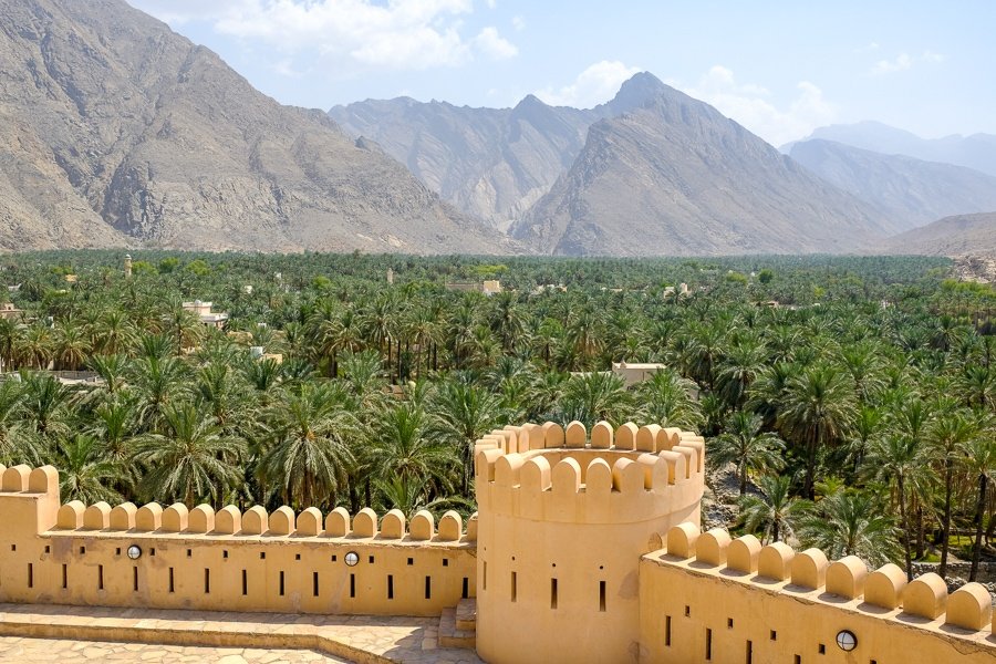 Muro y palmeras y montañas distantes cerca del fuerte Nakhal en Omán