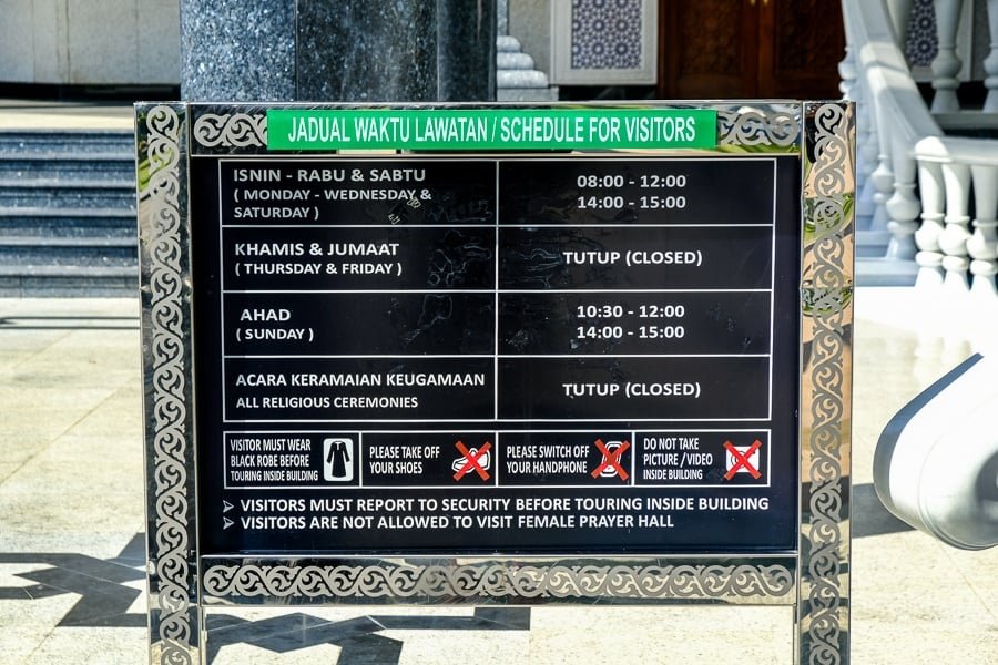 Señal de entrada que explica las reglas y horarios de entrada a la mezquita Jame'Asr Hassanil Bolkiah en Brunei