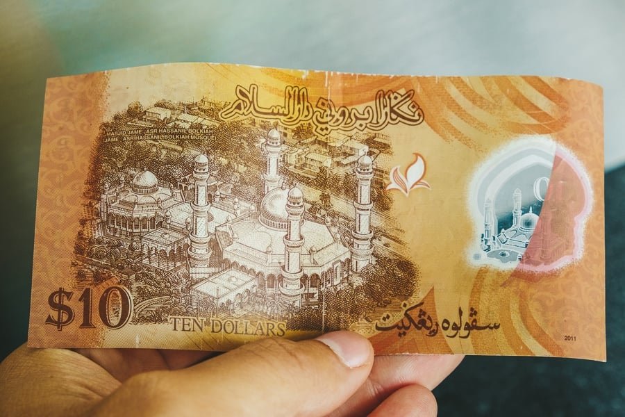 Mano sosteniendo un billete de dinero de Brunei de $10 dólares