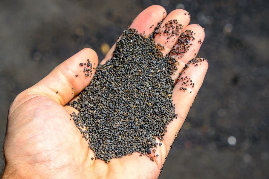 Mano sosteniendo arena negra en la Reserva Natural de Tangkoko en Sulawesi, Indonesia