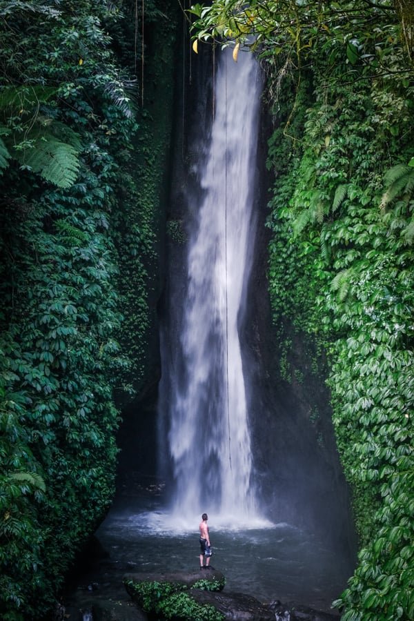 Un excursionista de pie en la cascada Leke Leke