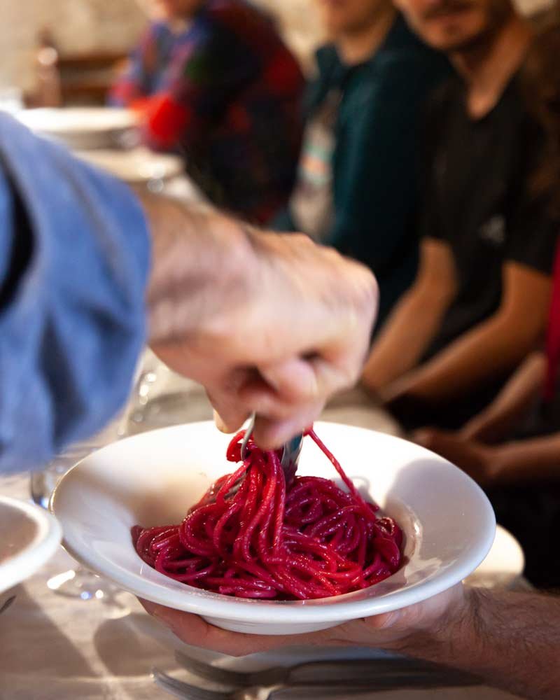 El camarero sirve un plato de pasta morada, coloreada por la remolacha con la que se hierve.